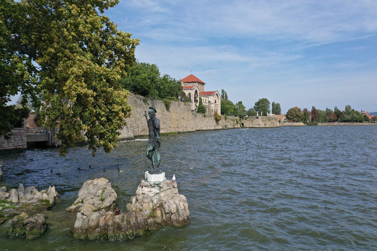 Keresztelõ Szent János szobra, N. Kovács Mária alkotása a hattyúetetõ sziklán, az Öreg-tóban. A háttérben a tatai vár.