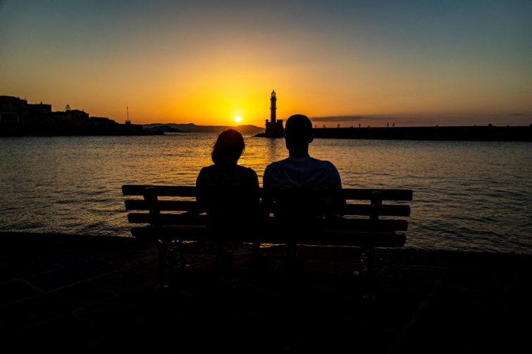 Egy pár gyönyörködik a naplementében Chania városának kikötőjében.
