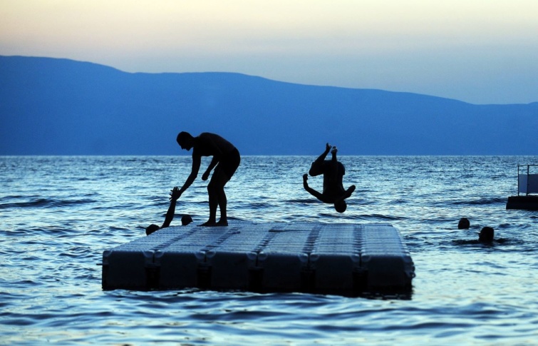 Egy férfi ugrik az Ohridi-tóba naplementekor Észak-Macedoniában