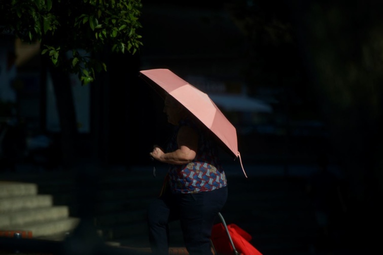 Egy nő esernyővel védi magát egy forró nyári napon Sevillában.