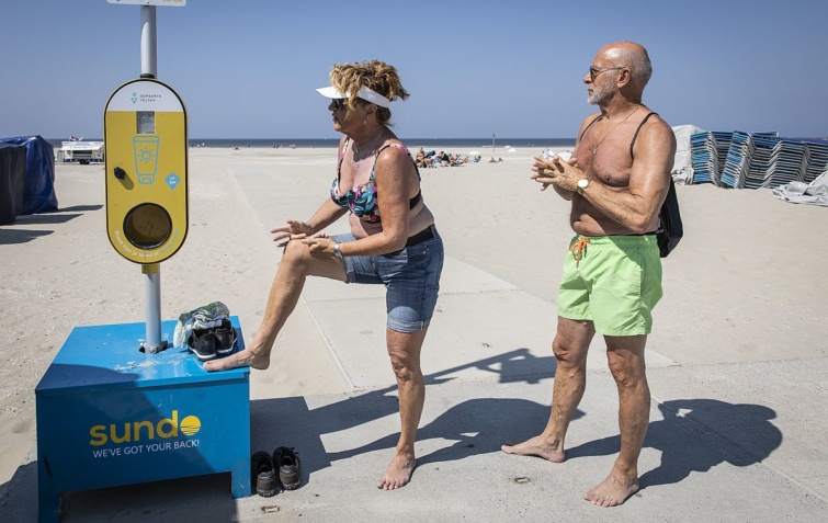 Ingyenesen használható naptejautomatából naptejet ken magára egy holland nő egy hollandiai strandon.