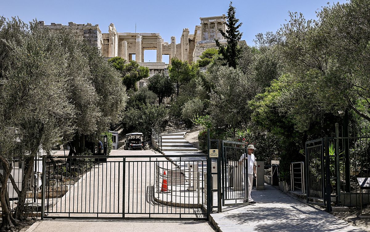 Egy férfi becsukja az athéni Akropoliszra vezetőút kapuját.