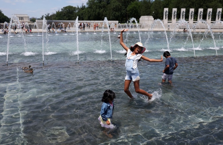 Utcai szökőkútban hűtik magukat az emberek a hőség idején