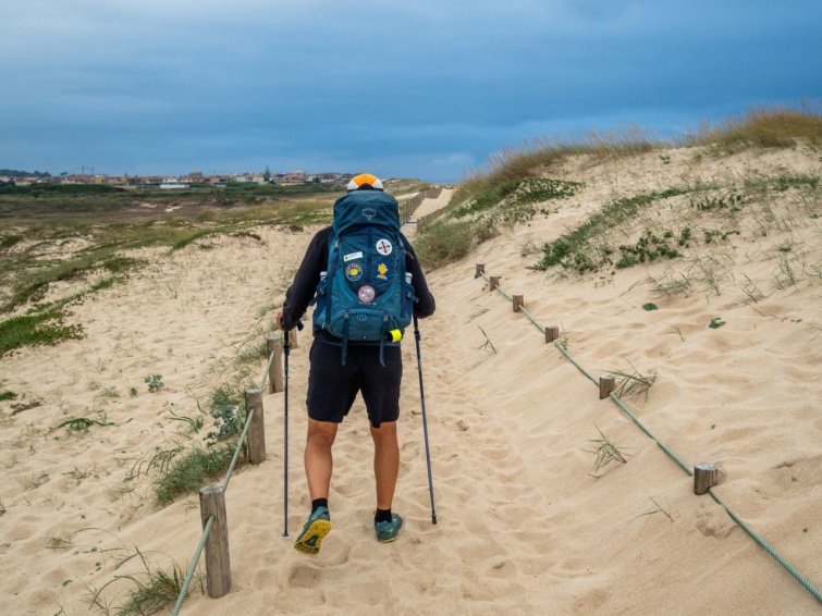 Egy túrázó próbál sétálni a homokon, miközben a portugál Camino tengerparti útvonalon sétál 