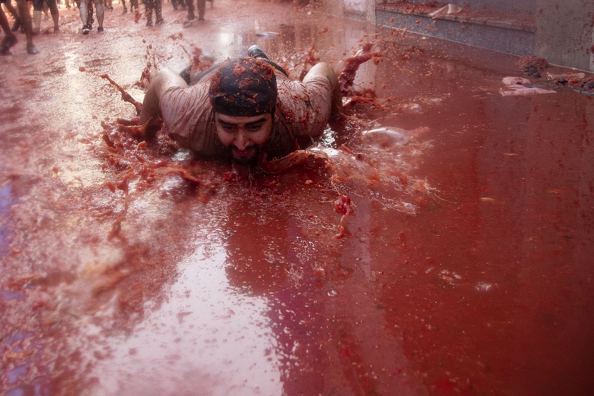 Un hombre yace en jugo de tomate en el Festival del Tomate.