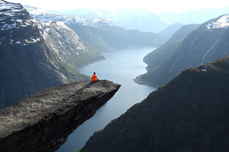 Egy utazó ül a norvégiai Trolltunga sziklaképződményen.