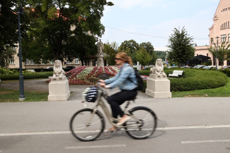 Egy nő biciklizik Eszéken, a Sakuntala Park előtt.