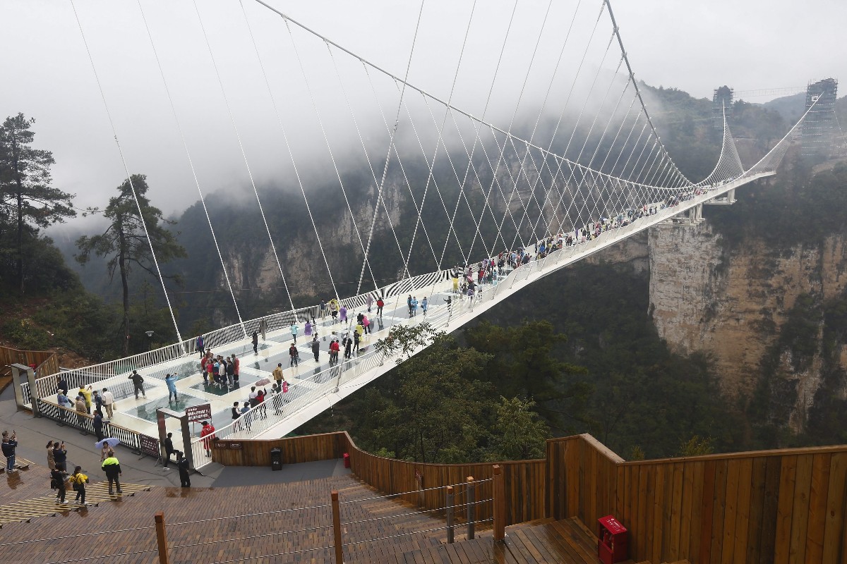 Üveghídon kelnek át turisták a Nagy Kanyonon a Hunan tartománybeli Csangcsiacsie városánál 2016. október 20-án.