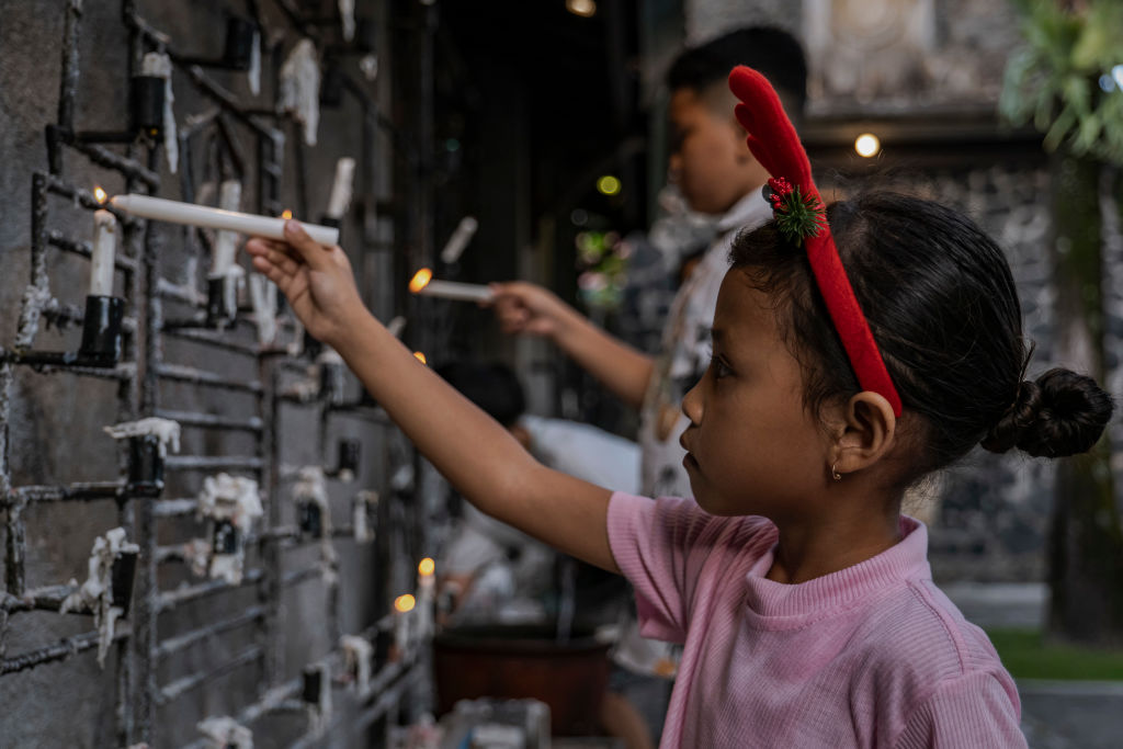 Egy indonéz keresztény gyermek gyertyát gyújt a karácsonyesti mise alatt Yogyakartában, Indonéziában. A világ legnagyobb muzulmán lakosságával rendelkező Indonéziában egy jelentős keresztény kisebbség is él, amely az ország 270 milliós lakosságának mintegy tíz százalékát teszi ki