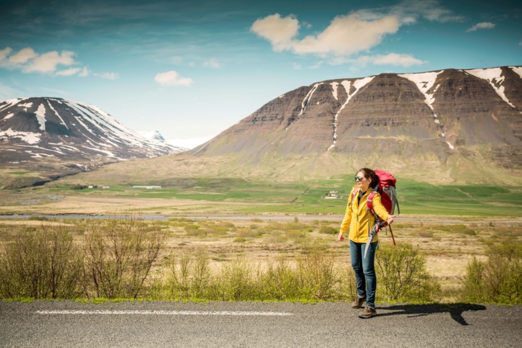 Egy nő stoppol az út szélén Izlandon