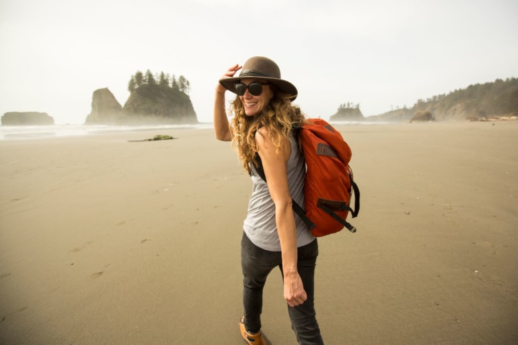 Utazó egy hátizsákkal kalapban egy tengerparton.