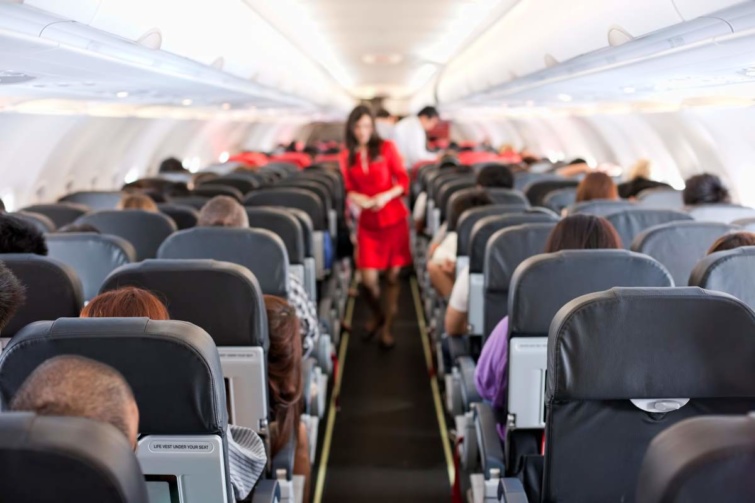 Piros ruhás nő egy repülőgép fedélzetén a sorok között