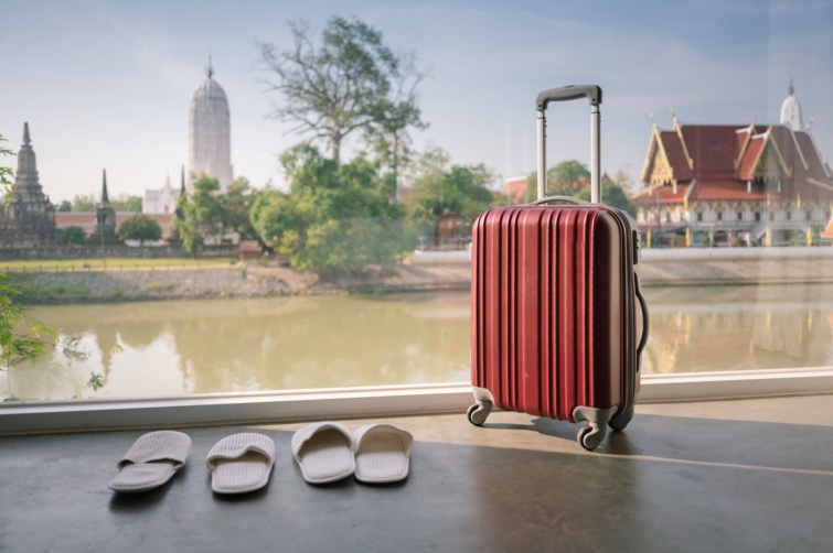 Bőrönd egy szálláson, a háttérben thaiföldi panoráma