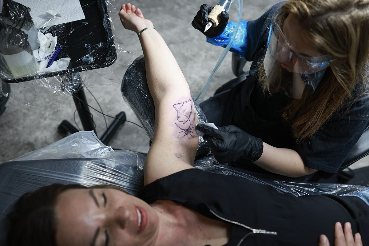 Nafogyatkozás-mintát tetoválnak egy nő karjára.