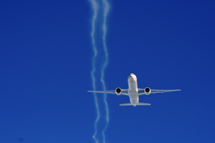 Egy boeing típusú gép repül, háttérben kék ég és kondenzcsík