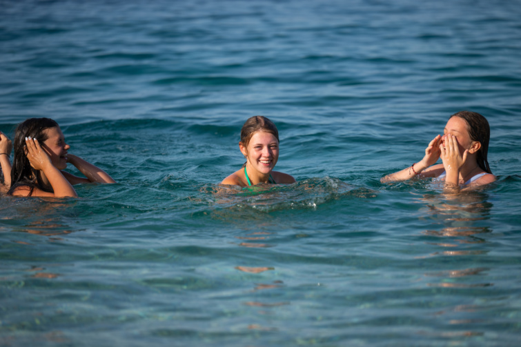 Három vidám fürdőző lány egy szabadstrandon a vízben