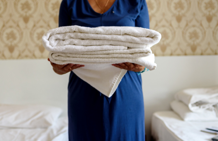Fehér törölközők kék ruhás nő kezében