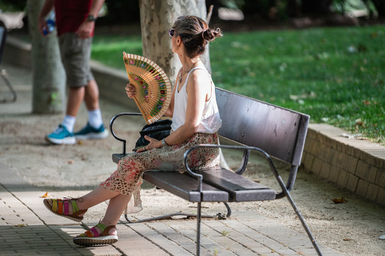 Most mész nyaralni? Van egy rossz hírünk - Startlap Utazás Egy nő egy park padján ülve legyezi magát a hőhullám okozta magas hőmérsékletben
