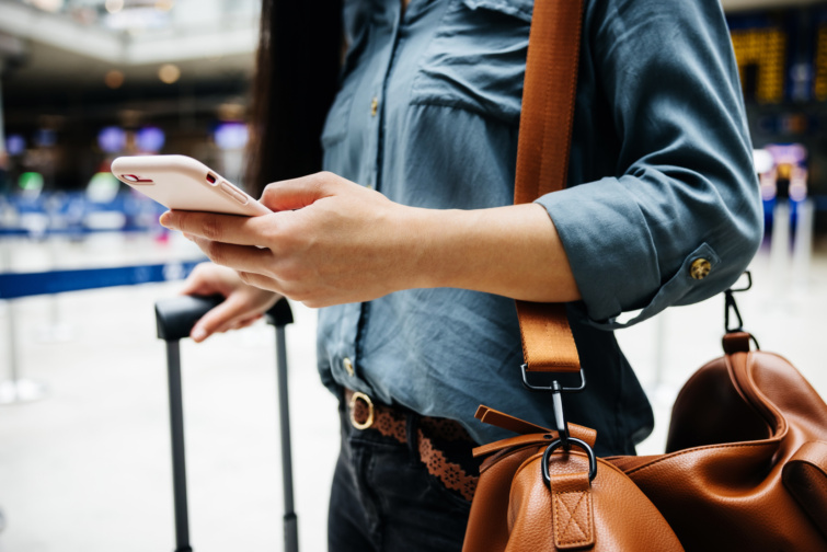 Reptéren nő táskával poggyásszal és telefonnal