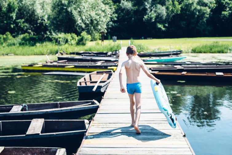 Kisfiú csónakkal a Tisza mellett egy stégen