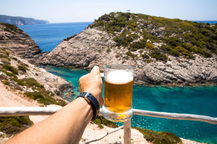 Hideg sör férfikézben tengerparti panorámával