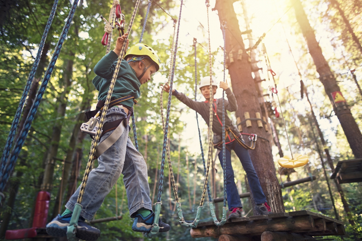 Sister helping her brother during ropes course in adventure park - Startlap Utazás