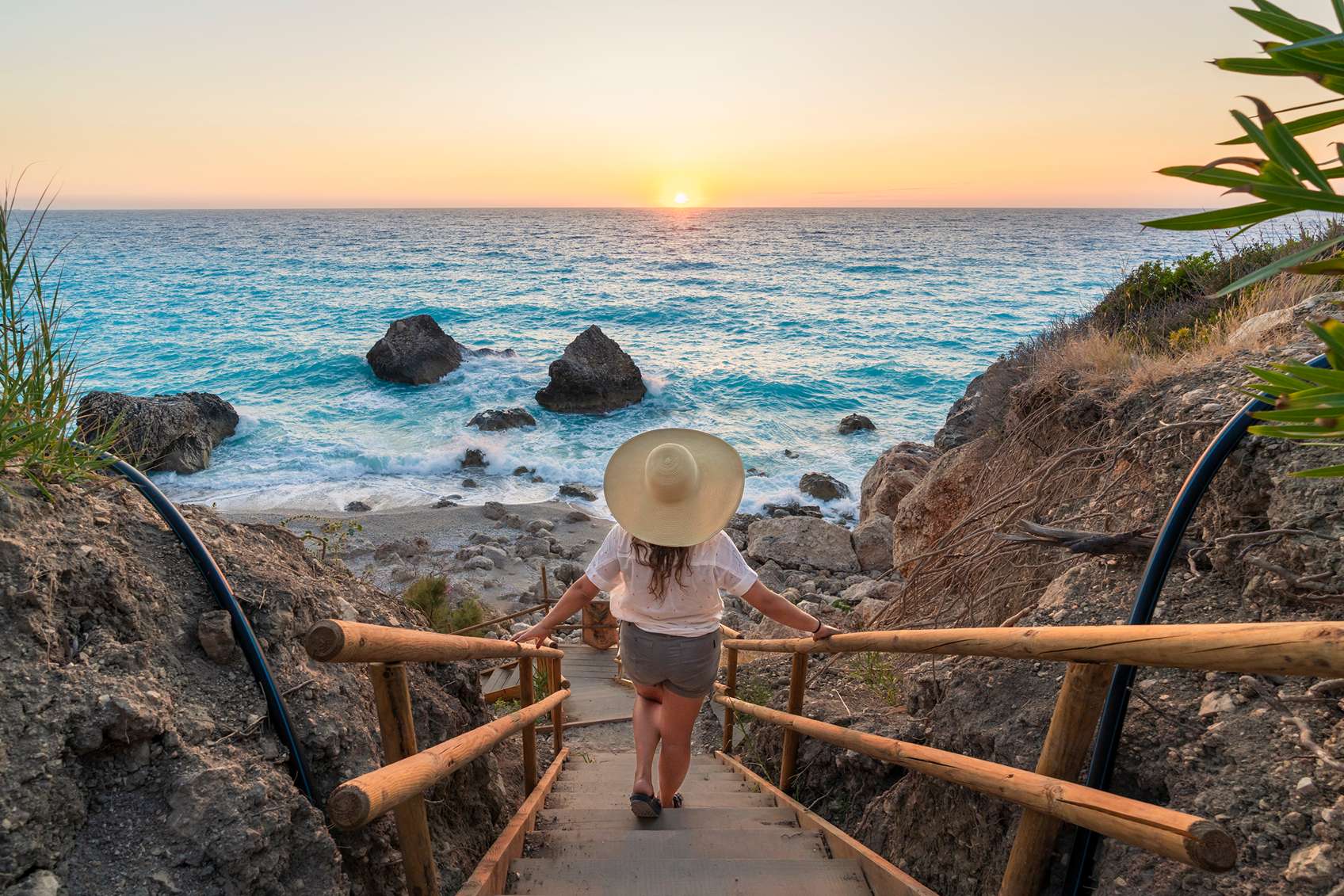 Kalapos nő sétál a part irányába