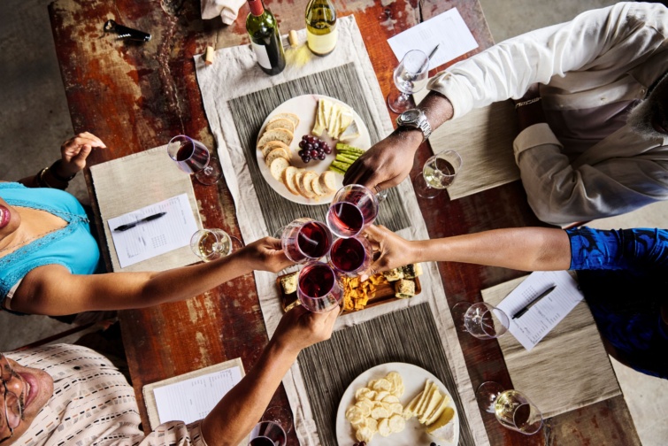 Turisták koccintanak borral egy éttermi asztal felett.