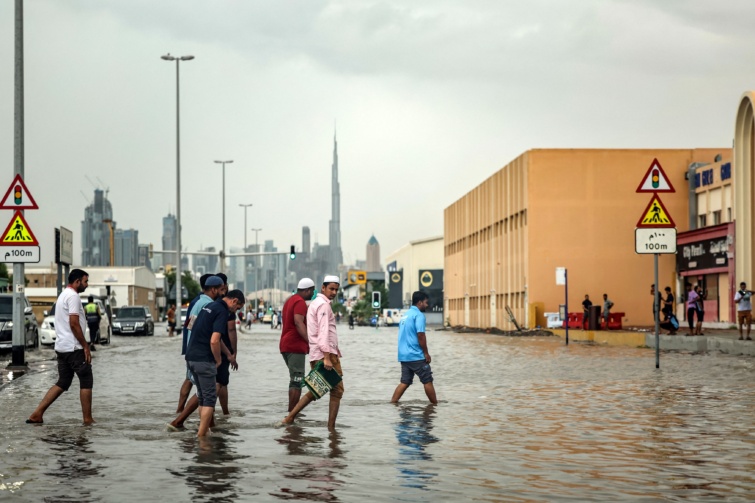Emberek sétálnak térdig érő vízben, a háttérben felhőkarcolók.