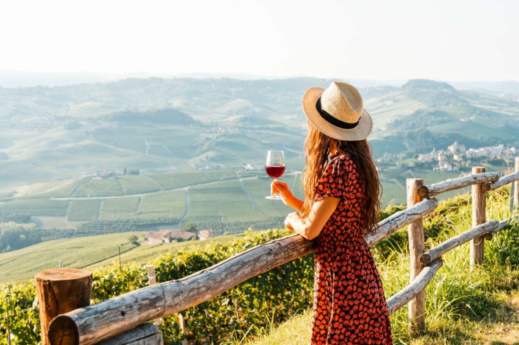Szép tájat néző nő pohár borral és kalappal a fején
