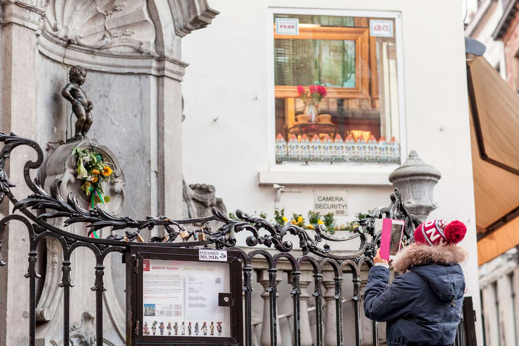 Pisilő kisfiú szobrot fotózó sapkás nő