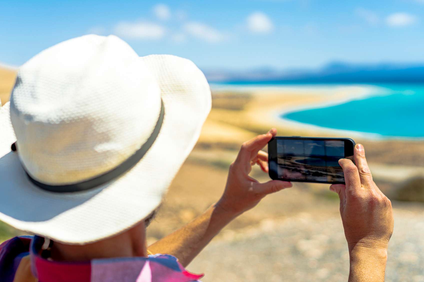 Tengerpartot fotózó kalapos ember hátulról
