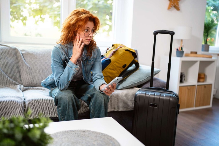 vörös hajú nő bőröndökkel kanapén nem túl vidáman