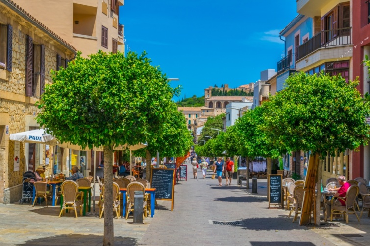 Arta városának utcácskája, kétoldalt fasorral, a háttérben egy étterem teraszával