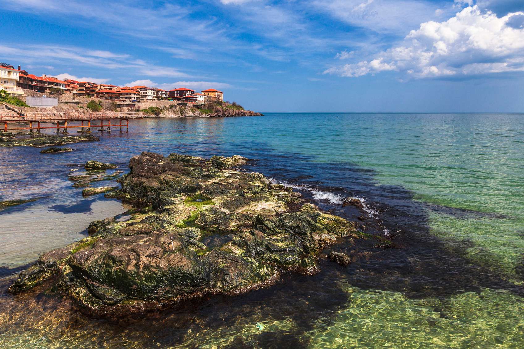 Sziklás tengerpart háttérben mediterrán várossal