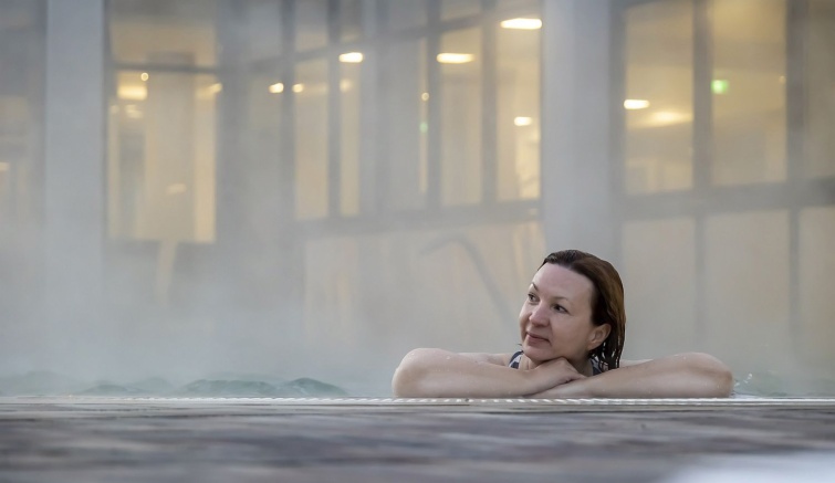 Egy középkorú nő relaxál egy fürdő medencéjében.