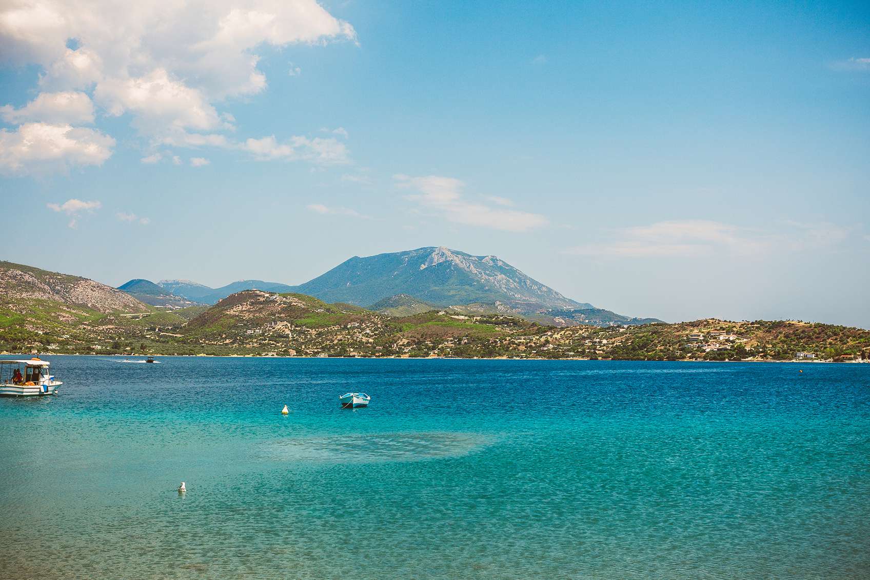 Kristálytiszta tenger háttérben hegyek és hajó
