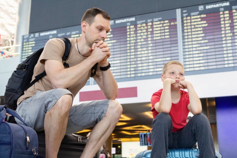 Egy apa és fia várakoznak egy repülőtéren, kissé fáradtan
