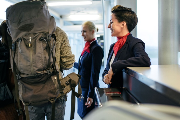 Mosolygó légiutas-kísérők figyelik a fedélzetre szálló utasokat.