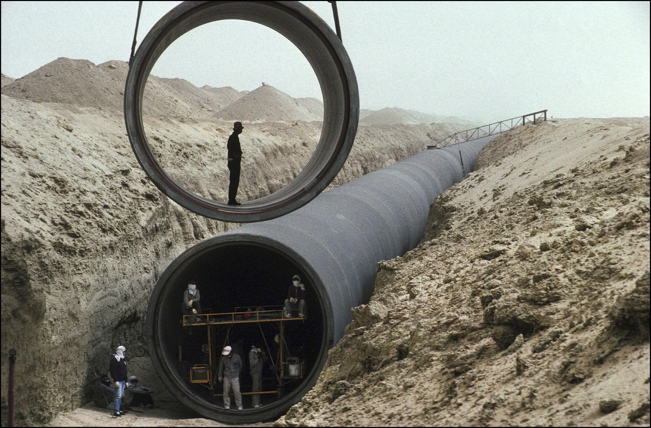 Betoncsövet emelnek a helyére, benne egy ember áll.