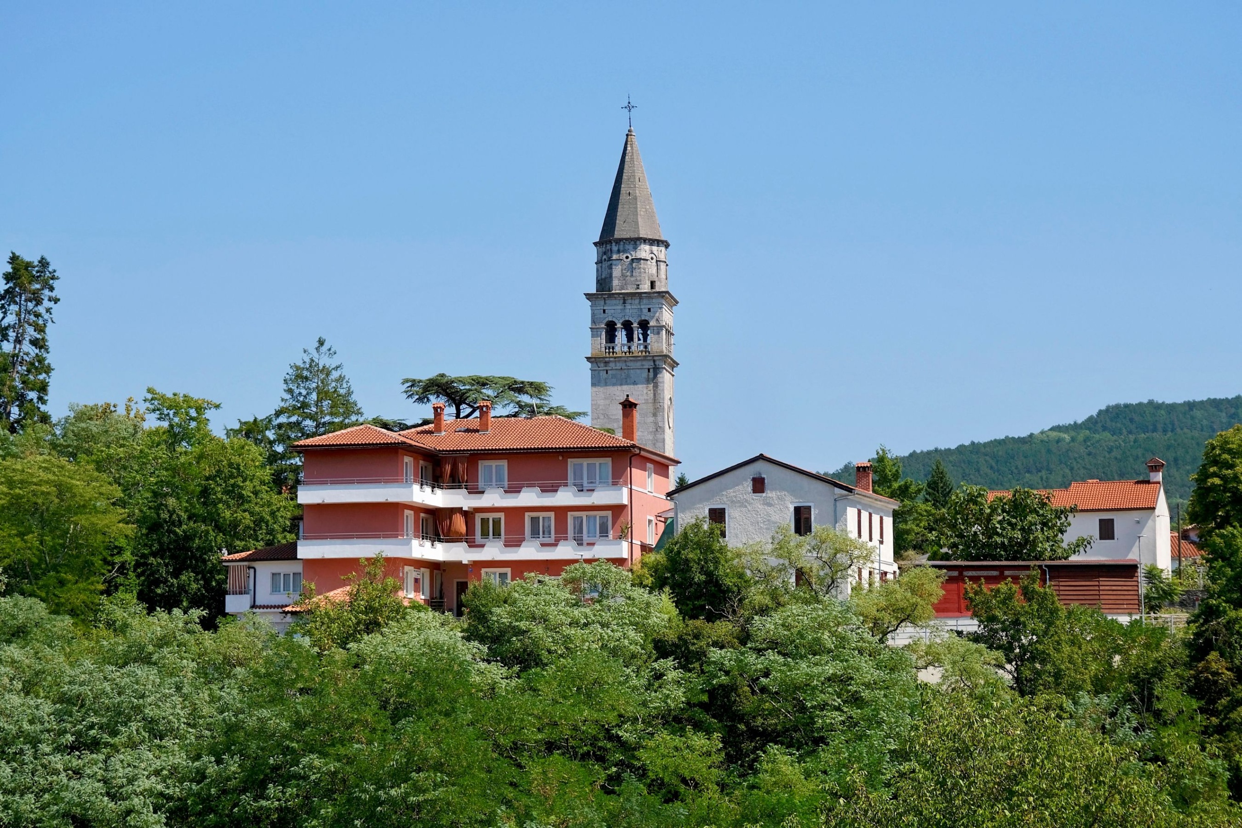 Templomtorony házakkal és zöld fákkal.
