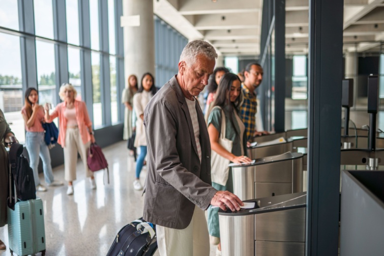 Idős férfi azonosítja magát útlevéllel a reptéren.