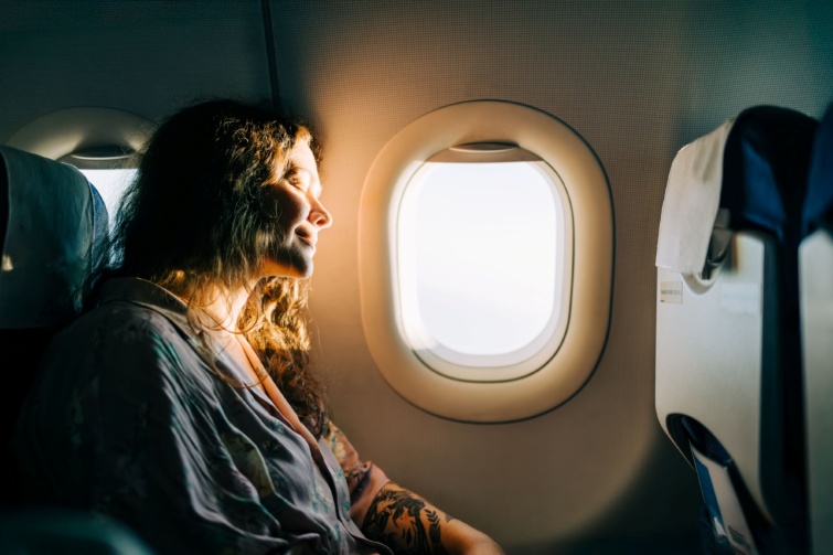 Mosolygó nő egy napos repülőablakkal.