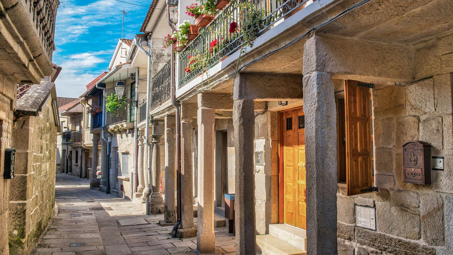 Macskaköves utca oszlopos házakkal virágokkal