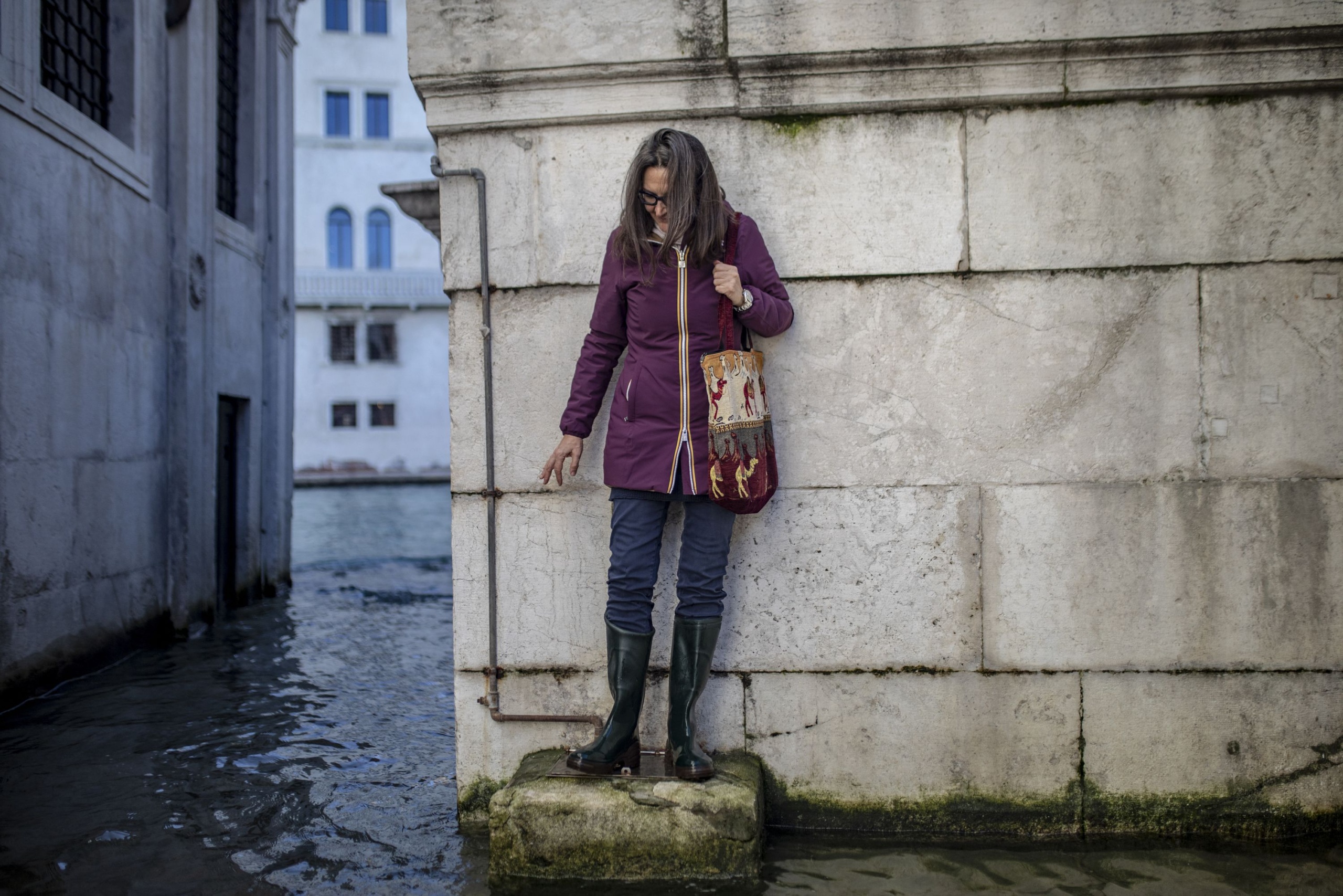 Turista térkövön áll, körülötte víz borítja az utcát.