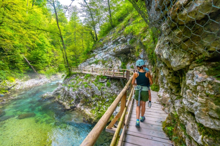 Fa pallón sisakban sétáló túrázó egy szurdokban.