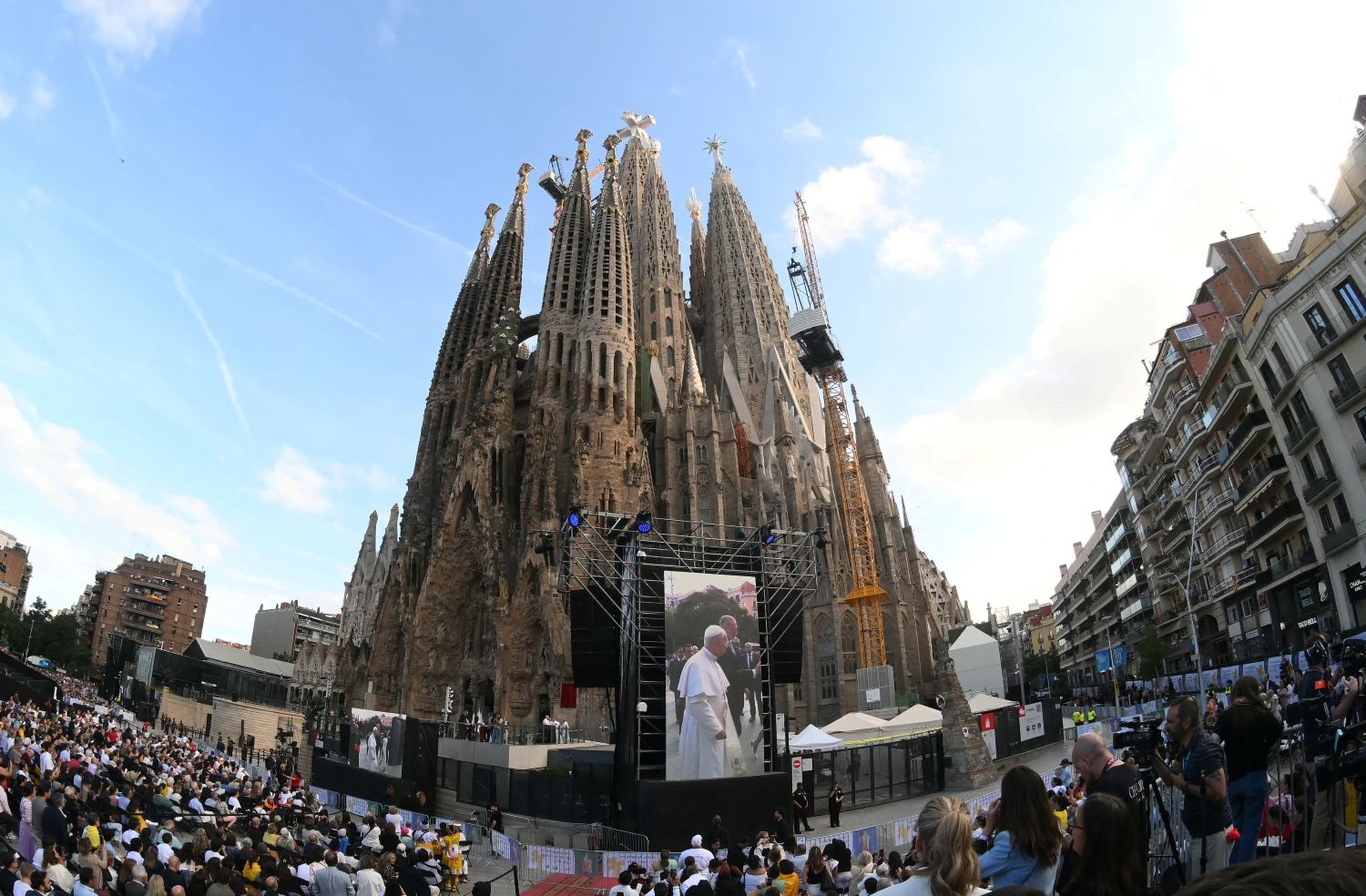 Kiveítőn a pápa, a Sagrada Família előtt, tömeg figyeli a történéseket.