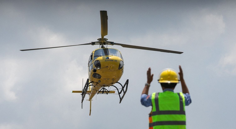Leszálló helikoptert irányít egy dolgozó.
