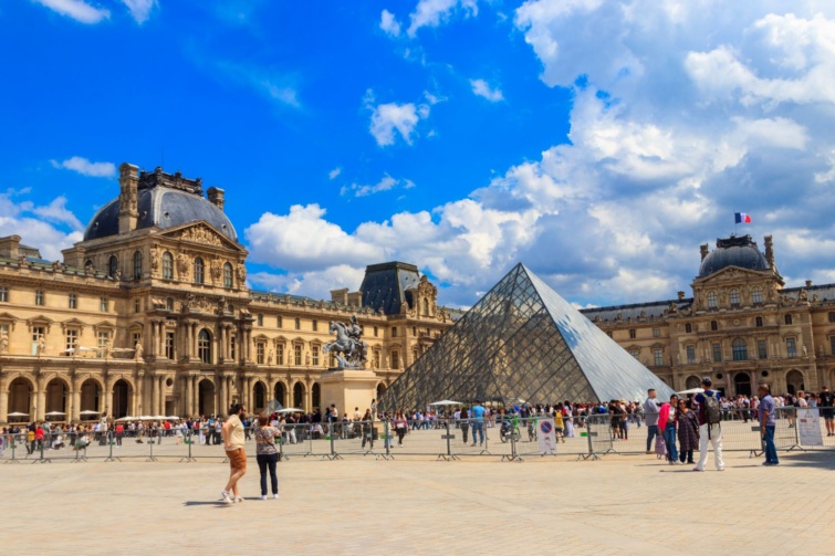 Fényes-nappal a párizsi Louvre nyári tájképe, szállíngózó turistákkal.
