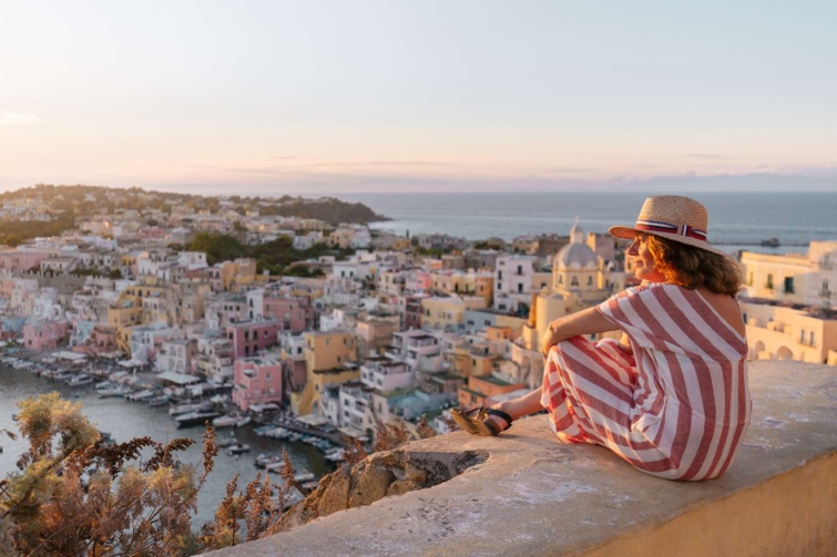 olaszorszag turista_11zon - Startlap Utazás panorámás kilátás a városra, kalapos nő ül a padka szélén